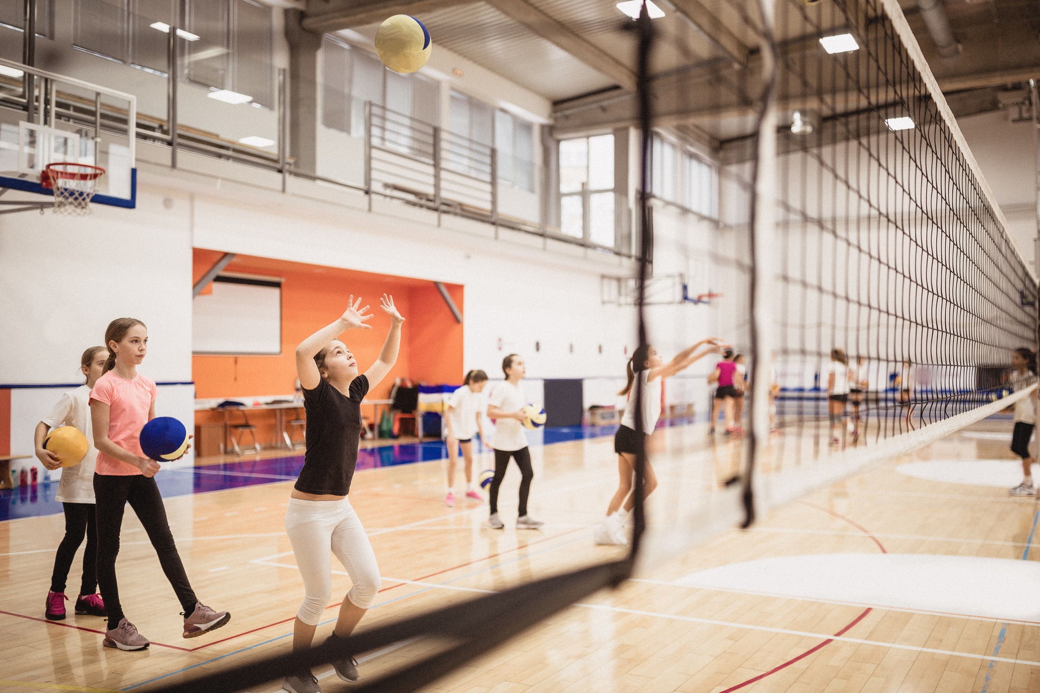 Female volleyball team exercising indoors on volleyball court