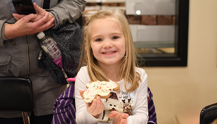 child smiling and holding gingerbread cookie